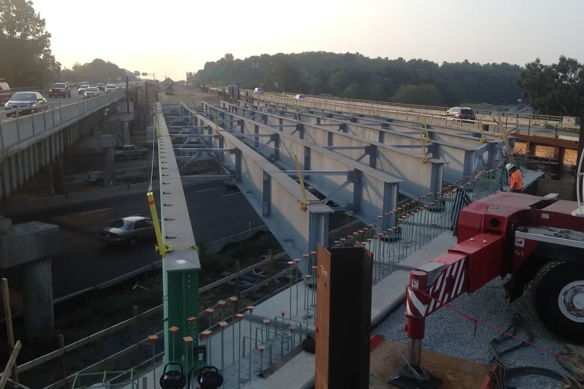 Steel I-beams being erected as bridge girders over a highway
