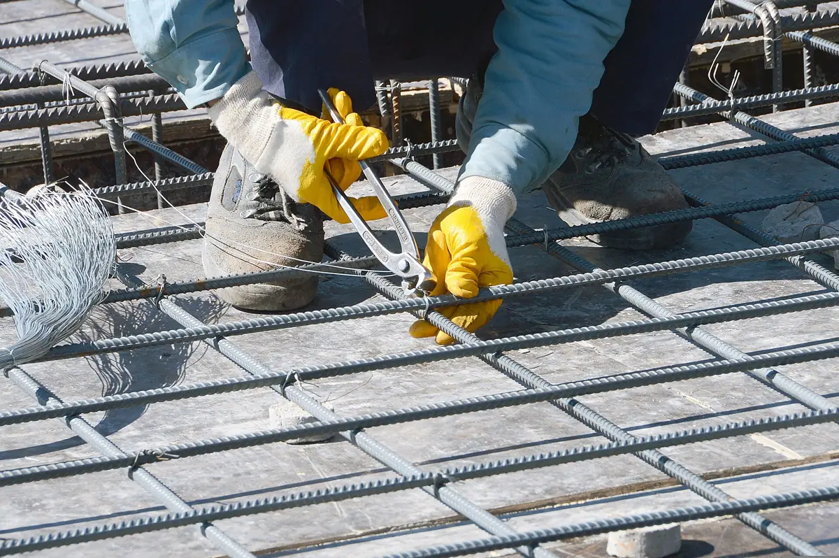 A worker tying steel reinforcing bars for a concrete floor